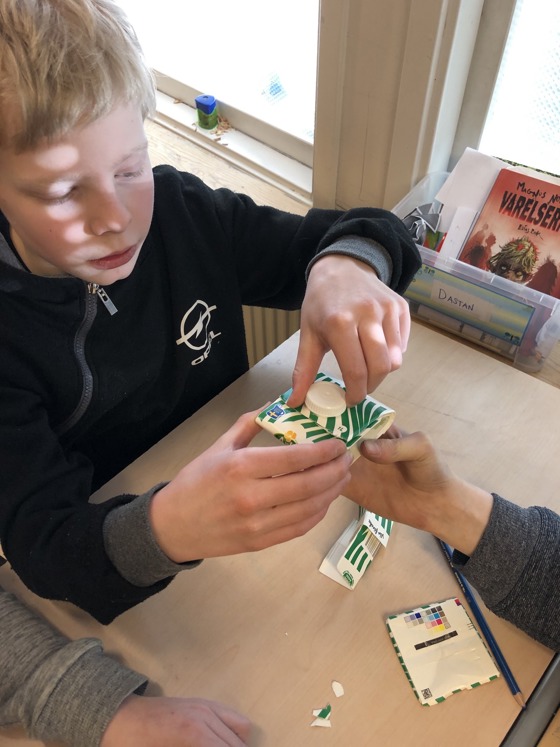 En elev viker en plånbok av ett gammalt mjölkpaket